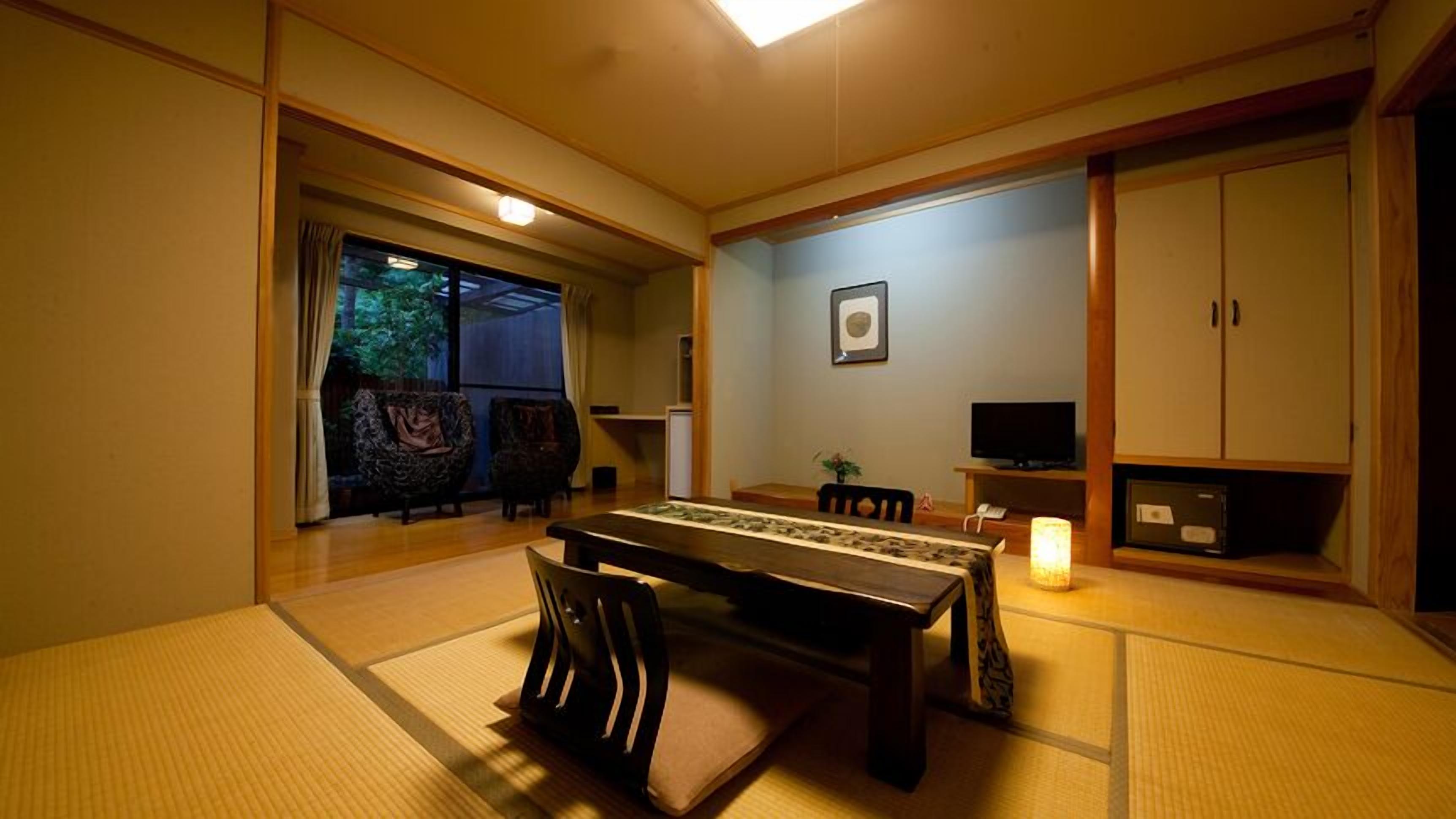 A traditional Japanese room with tatami flooring, a low table, chairs, a television, and a cabinet.