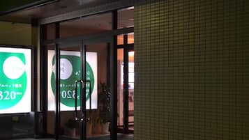 Entrada de un edificio con puertas de vidrio y un cartel verde.
