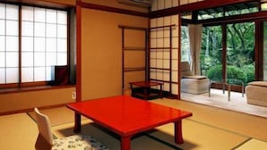 Ett traditionellt japanskt rum med tatamimattor på golvet, ett lågt träbord och skjutbara shojidörrar.