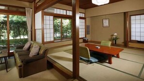 Ett traditionellt japanskt rum med tatamimattor på golvet, ett lågt bord och en soffa.