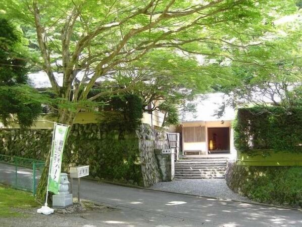 A pathway leading to a building with a stone wall and a tree. - Yugawara Onsen Kamata (Yugawara)
