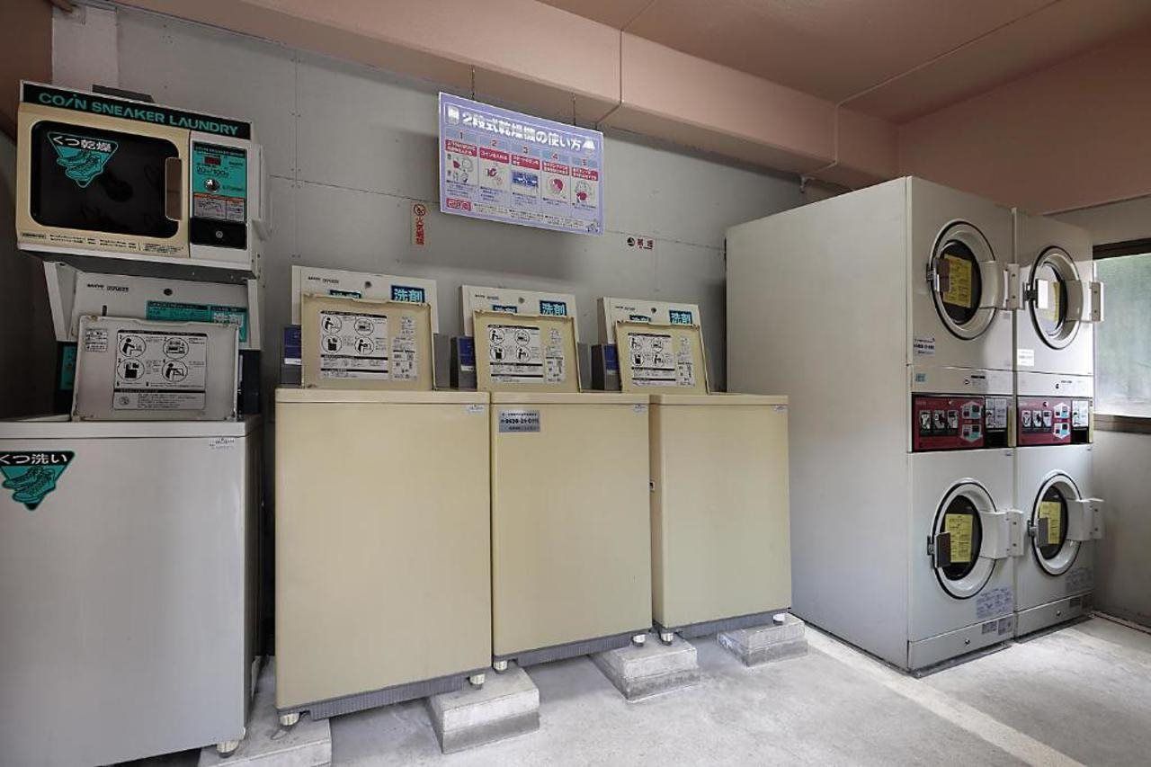 A laundry facility with multiple washing machines, dryers, and a control panel.