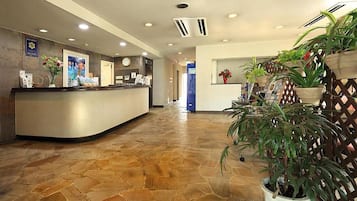 A reception area with a curved reception desk, a clock, and a wall-mounted sign.
