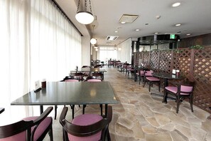 A restaurant with tables and chairs, a stone floor, and a view through a window with curtains. - Kumegawa Wing Hotel (Higashimurayama)