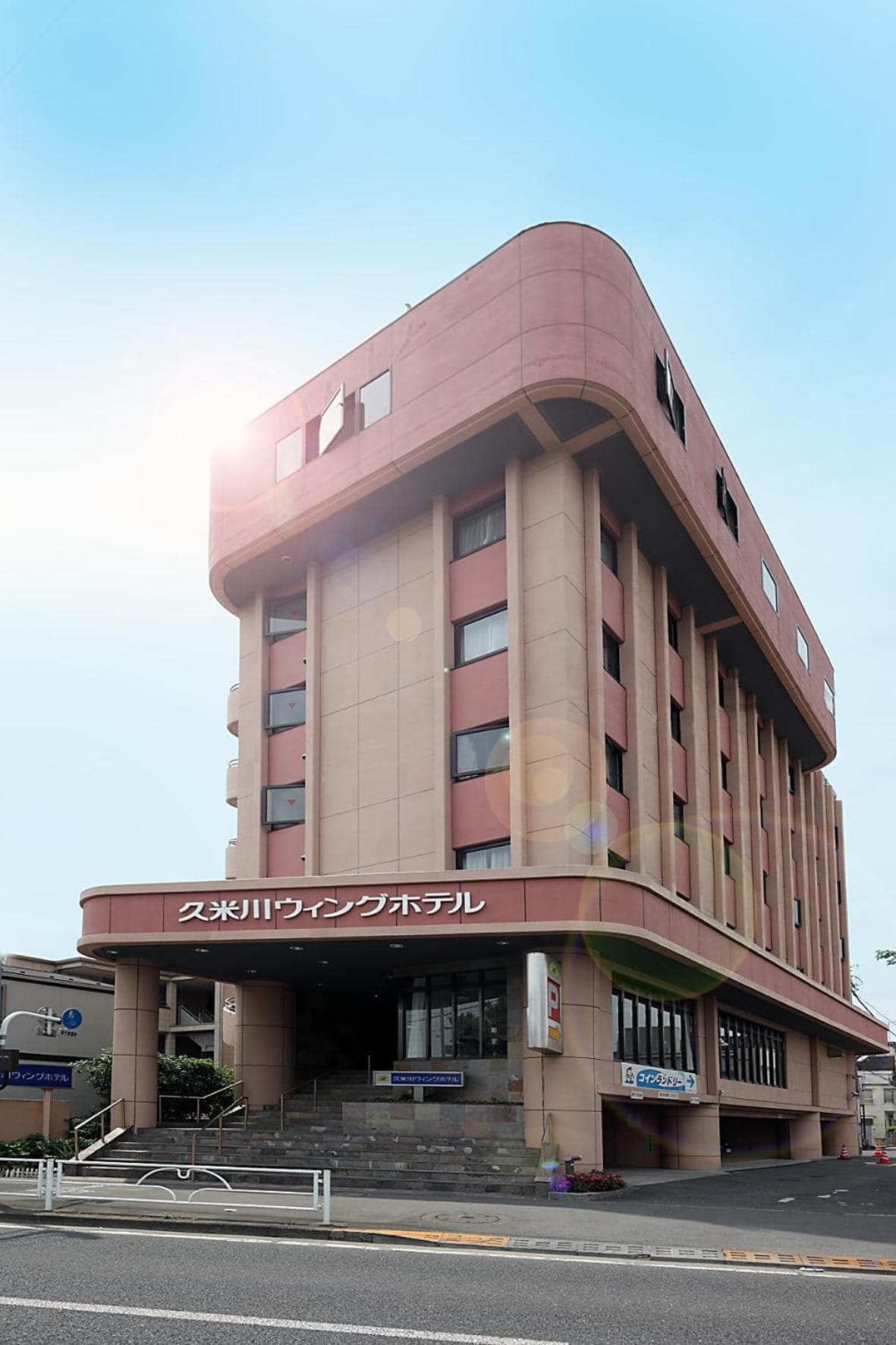 A multi-story building with a curved facade, a prominent entrance, and signage indicating it is a hotel.