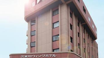 A multi-story building with a curved facade, a prominent entrance, and signage indicating it is a hotel.