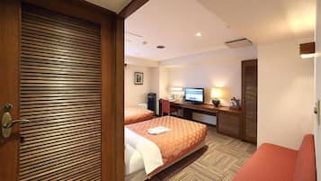 A hotel room with two beds, a desk with a computer, a television, and a red chair.