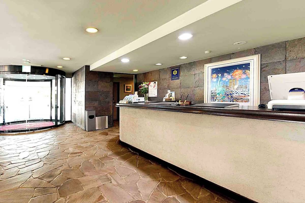 A reception area with a stone-tiled floor, a reception desk, a framed picture, and a door leading outside.
