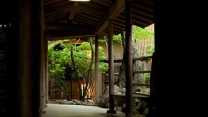 Ein traditionelles japanisches Gebäude mit Holzkonstruktion, einem Kiesweg und üppigem Grün.