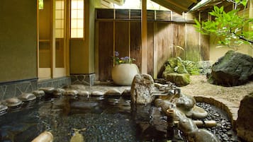 A traditional Japanese garden with a koi pond, rocks, and a wooden fence.