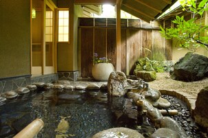 A traditional Japanese garden with a koi pond, rocks, and a wooden fence.