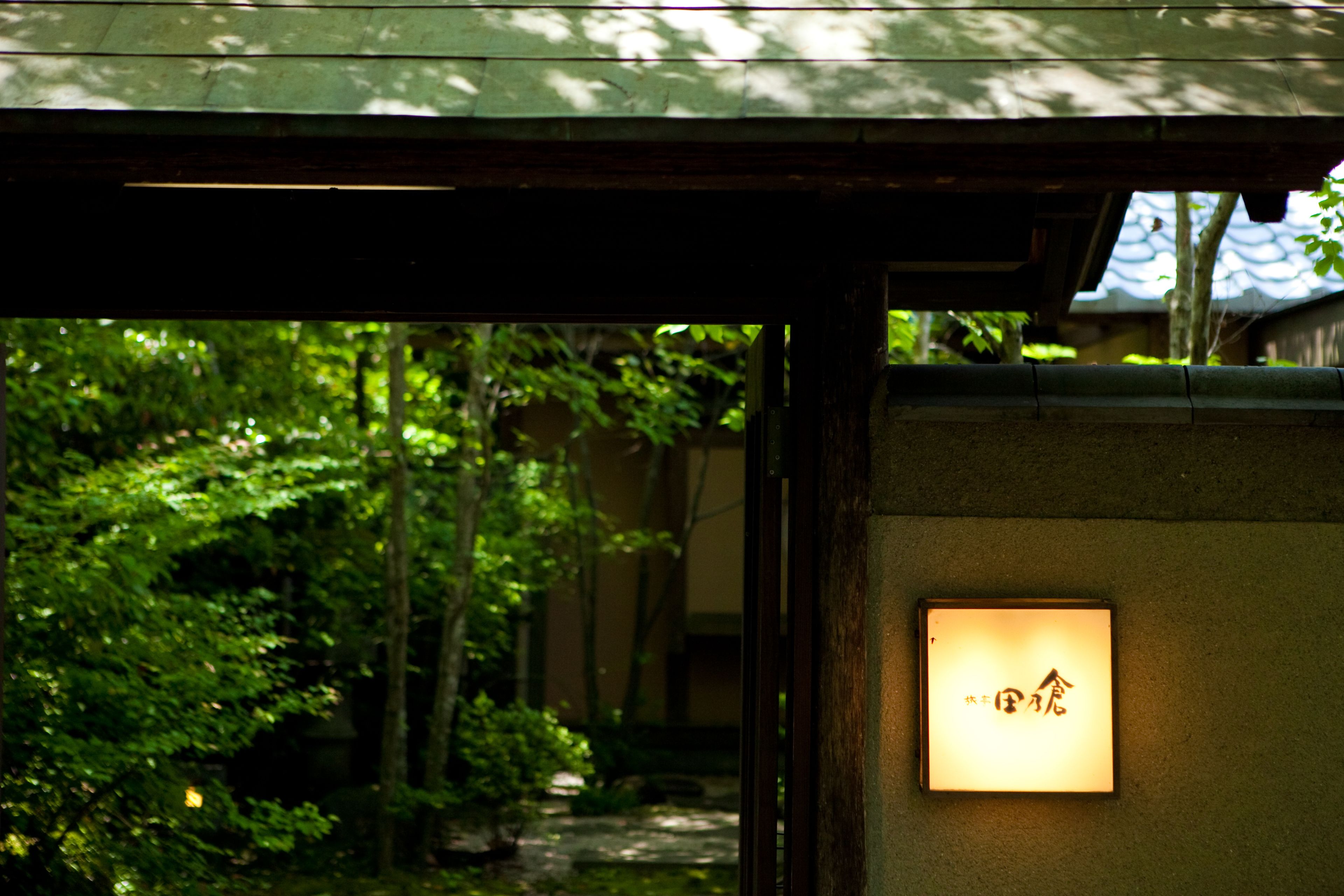 A traditional Japanese entrance with a wooden structure and a lit signboard.