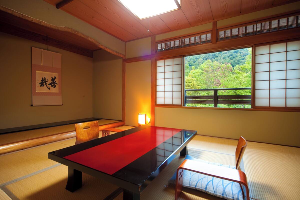 Ein Raum mit Tatami-Böden, einem niedrigen Tisch, Stühlen und einem Shoji-Bildschirm.