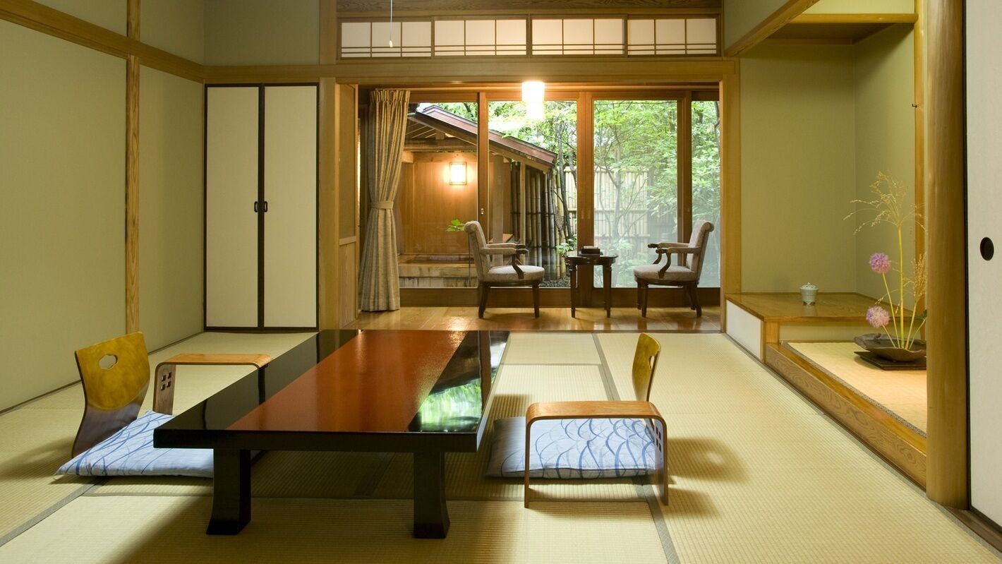 A traditional Japanese room with tatami flooring, a low table, and chairs.