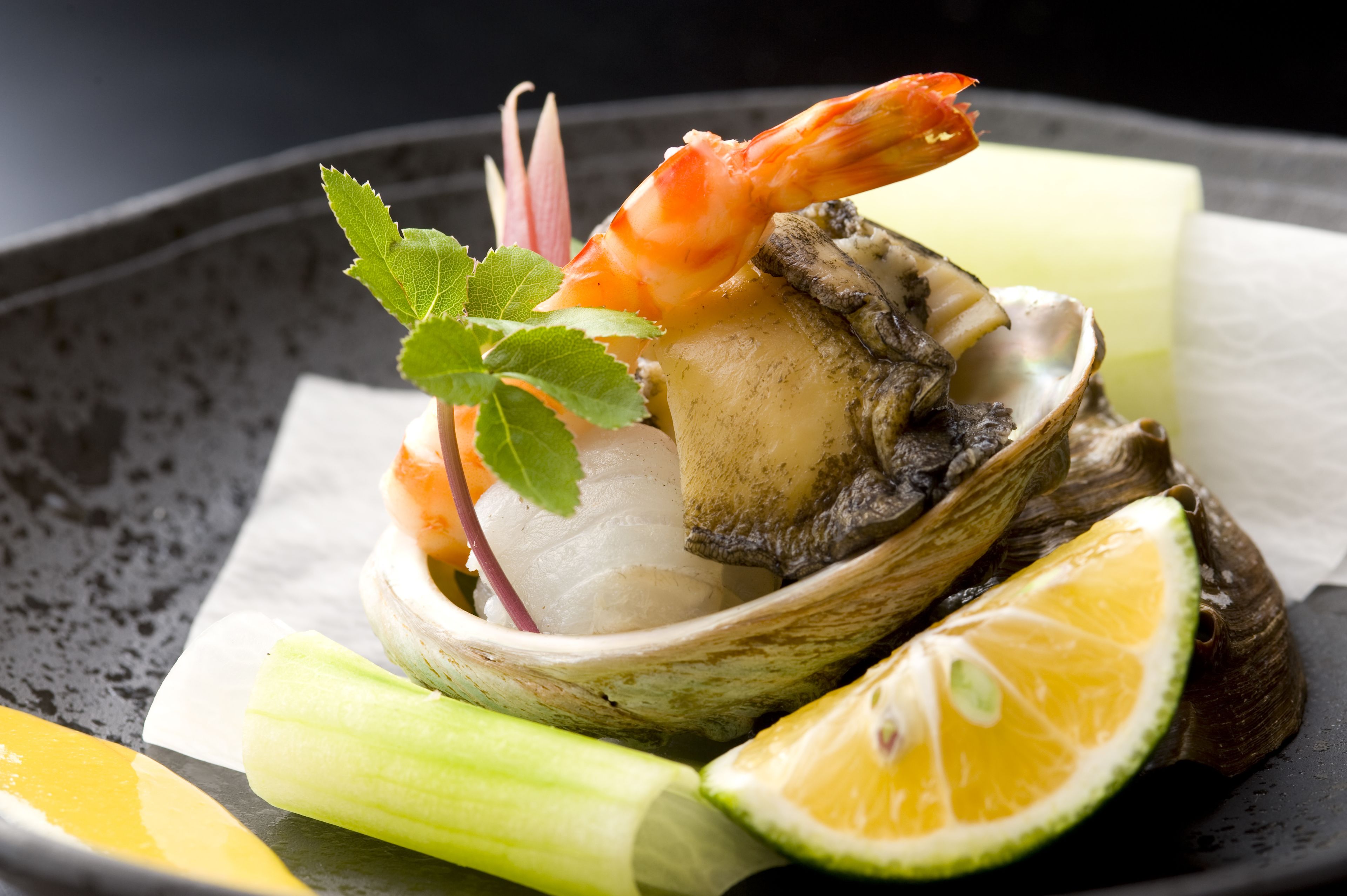 Un plato de mariscos con camarones, almejas, limón y apio.