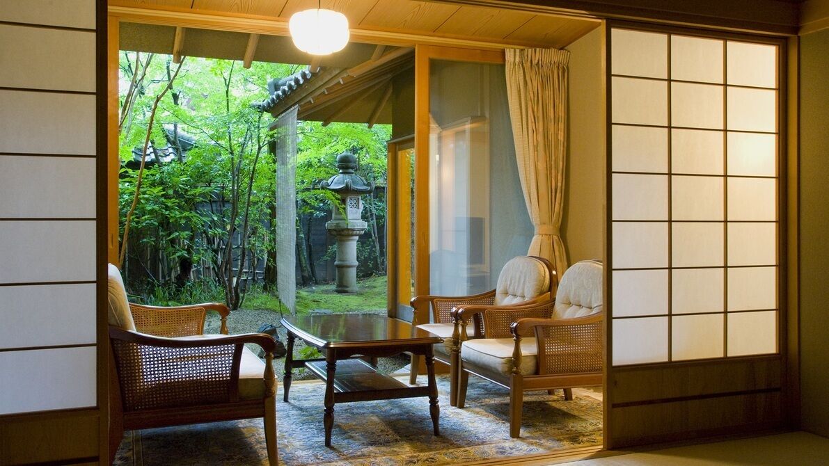 A traditional Japanese room with tatami flooring, a low table, and two chairs.