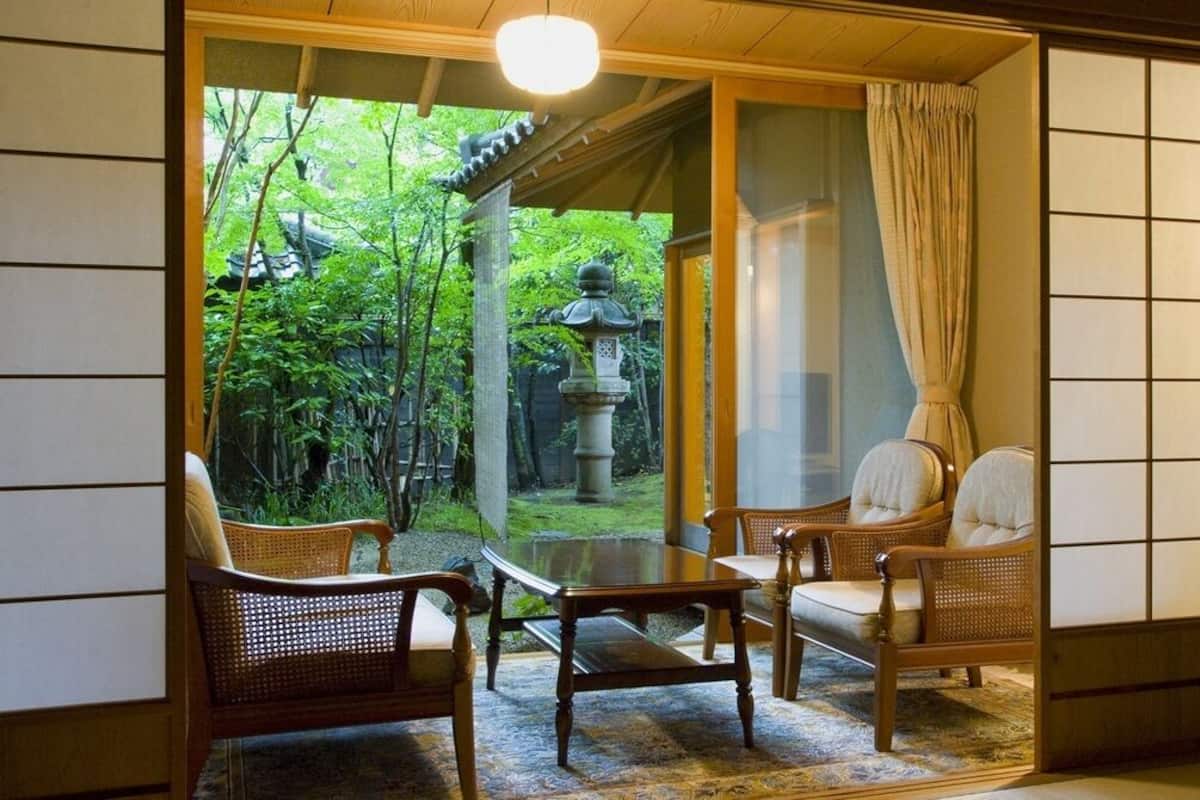 Una habitación japonesa tradicional con suelo de tatami, una mesa baja y dos sillas.