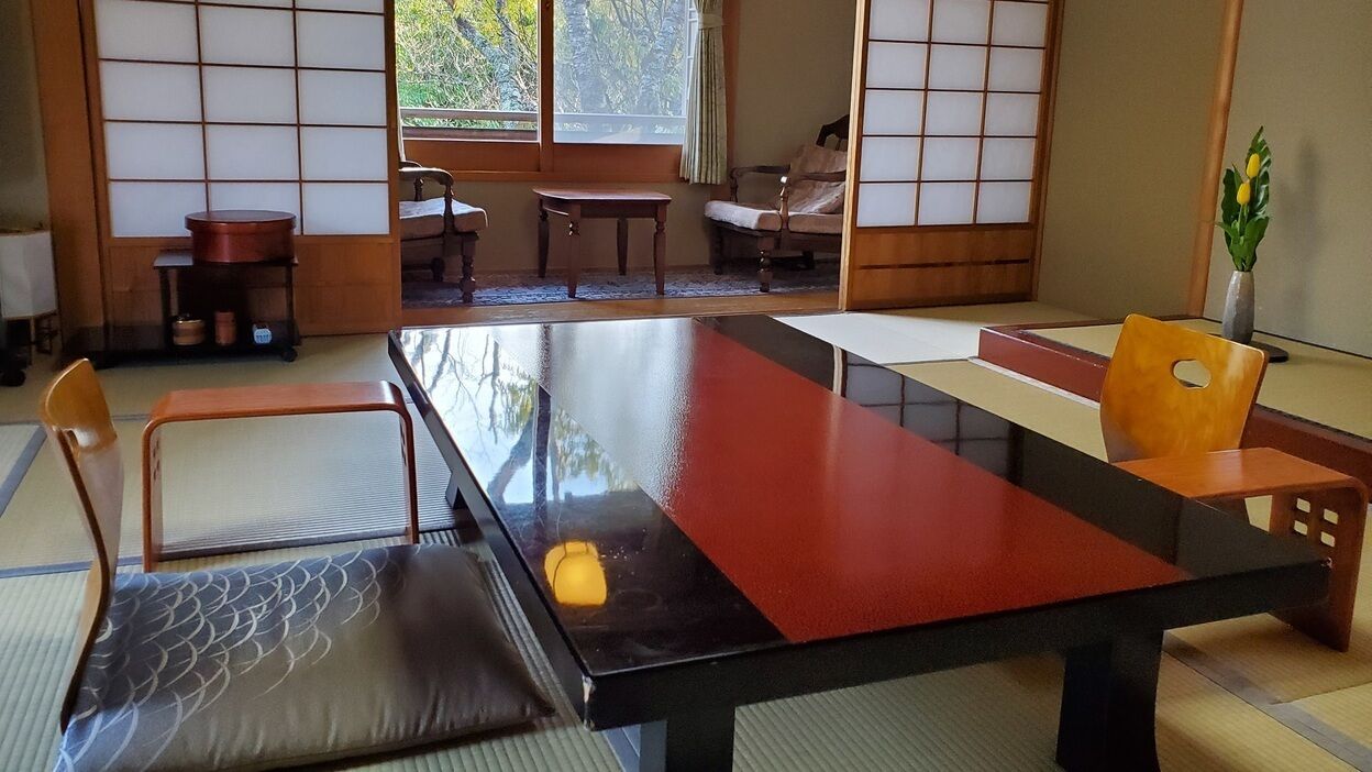A traditional Japanese room with tatami flooring, a low table, and a cushioned chair.