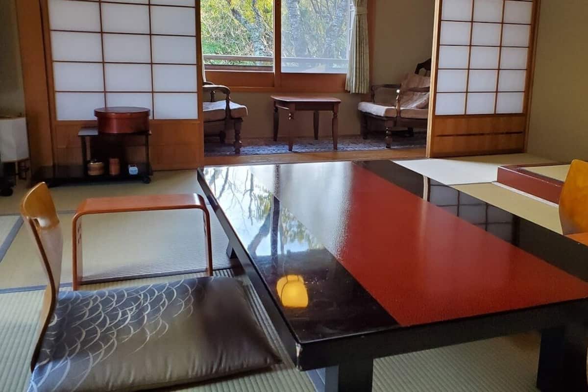 Una habitación japonesa tradicional con suelo de tatami, una mesa baja y una silla acolchada.
