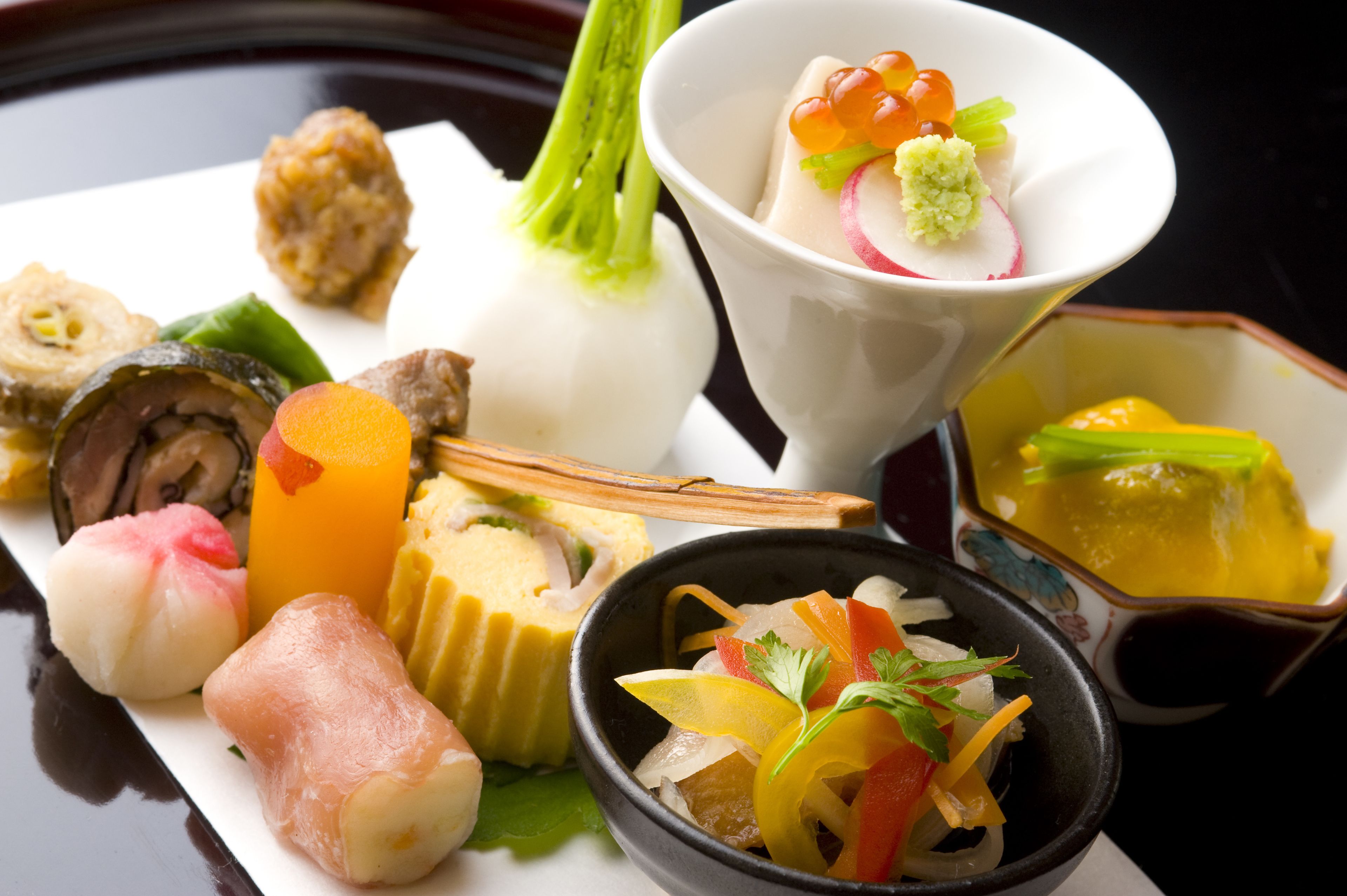 A variety of Japanese dishes including sushi, sashimi, and a bowl of pickled vegetables.