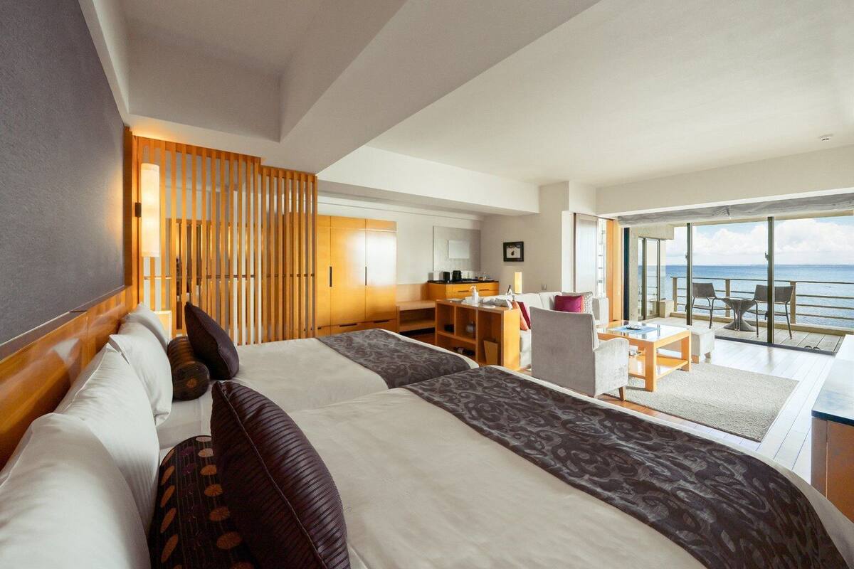Una habitación de hotel moderna con una cama grande, un escritorio y un balcón con vista al mar.
