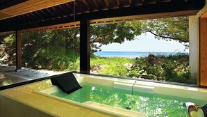 A glass-enclosed hot tub with a view of the beach and greenery. - Hyakuna Garan (Nanjo)