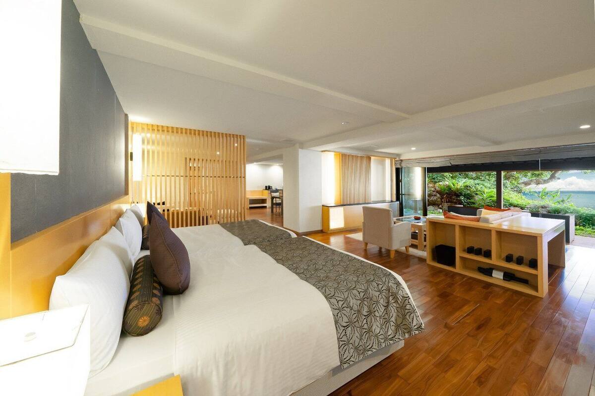 Una habitación de hotel moderna con una cama grande, un escritorio y vistas a zonas verdes.