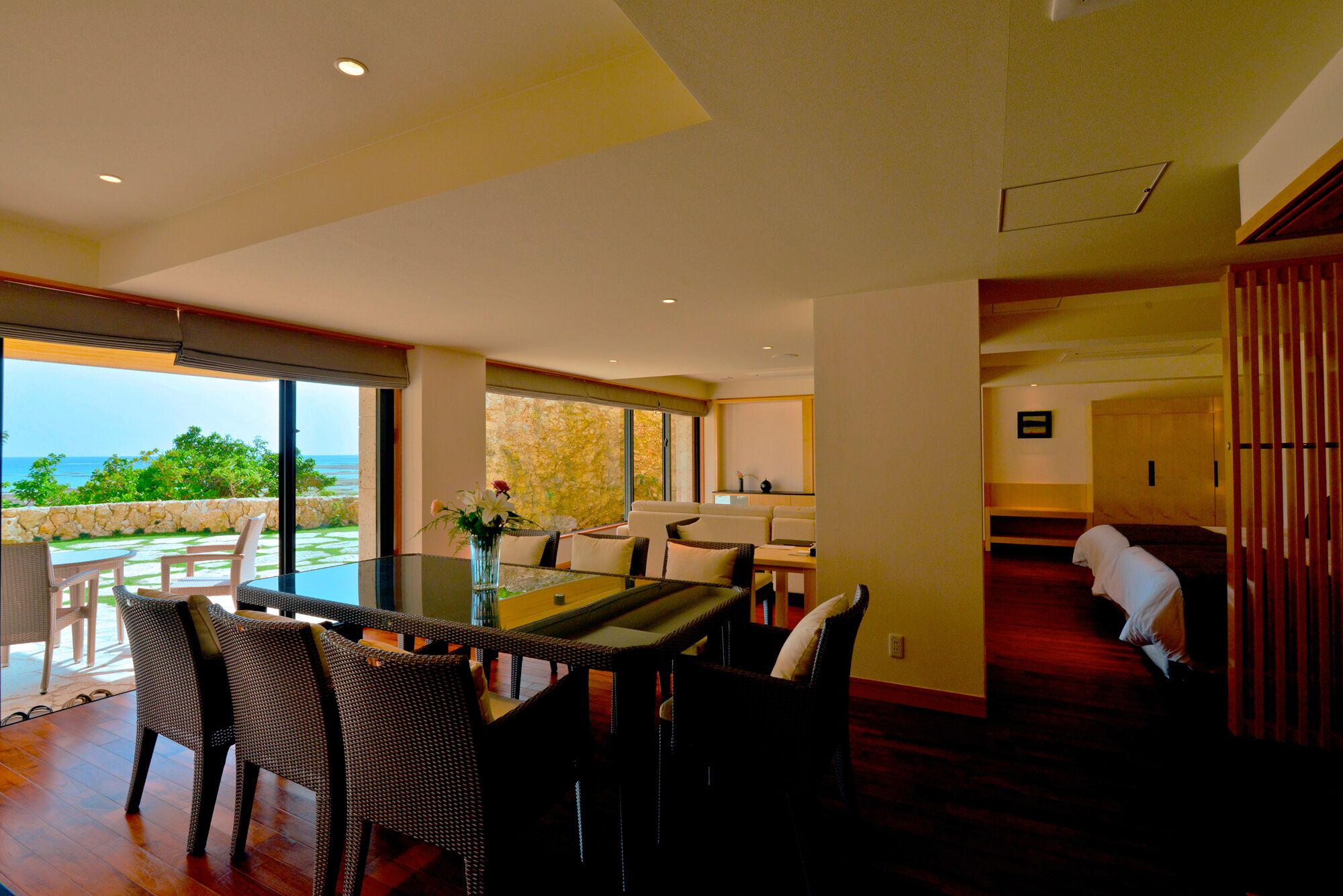 Una habitación amplia con una gran mesa de comedor, sillas de mimbre y vista al océano.