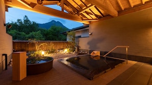 Un espace bien-être comprenant un jacuzzi, une terrasse en bois et une vue sur les montagnes.