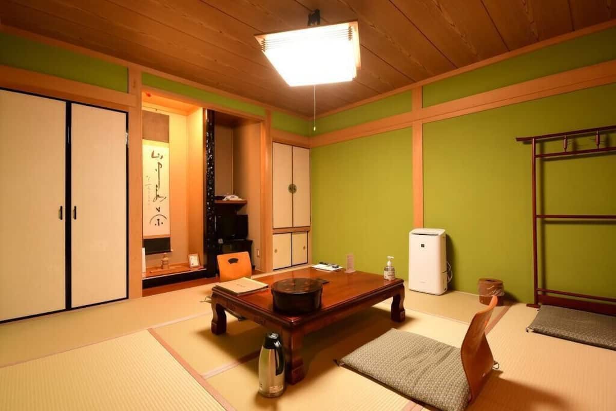 A traditional Japanese room with tatami flooring, a low table, a heater, and a television.
