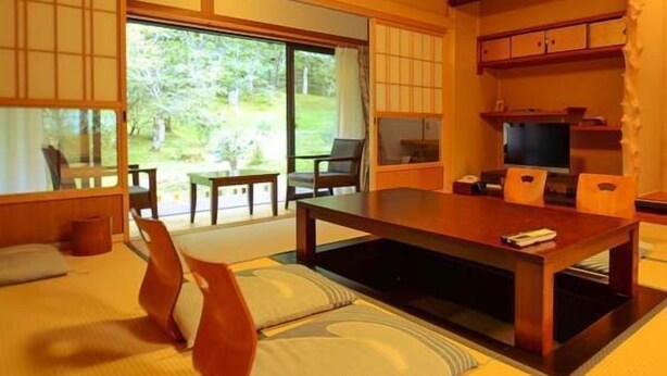 A traditional Japanese-style room with tatami flooring, a low table, and sliding doors leading to a garden. - Fudou-in (Koya)