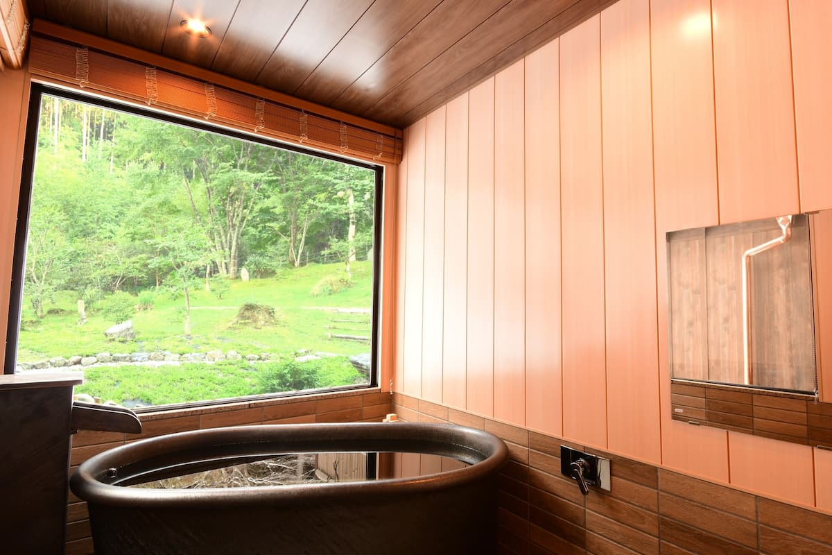 A bathroom with a large window, a bathtub, and a shower.