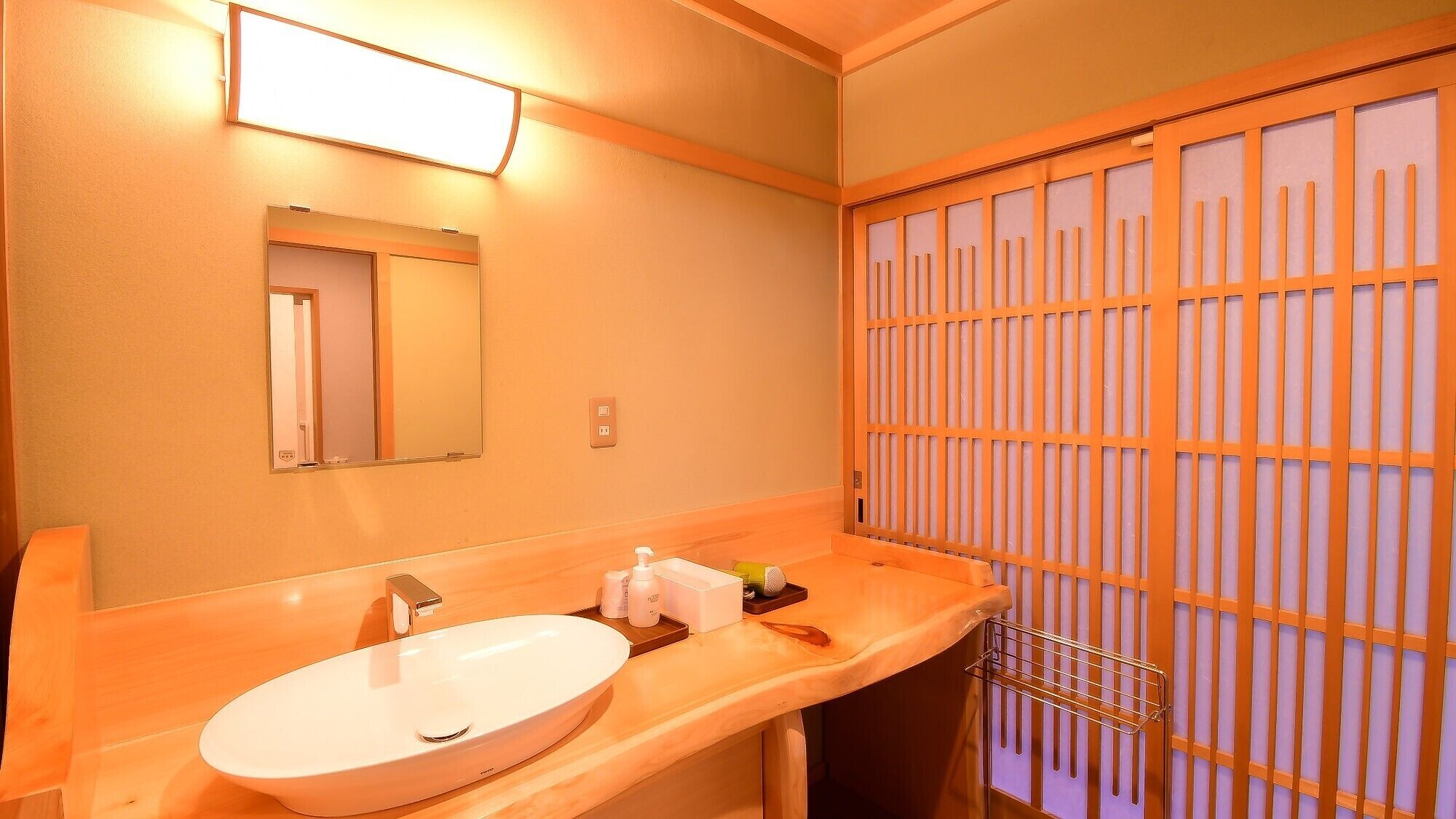 A hotel bathroom with a sink, mirror, and towel rack.