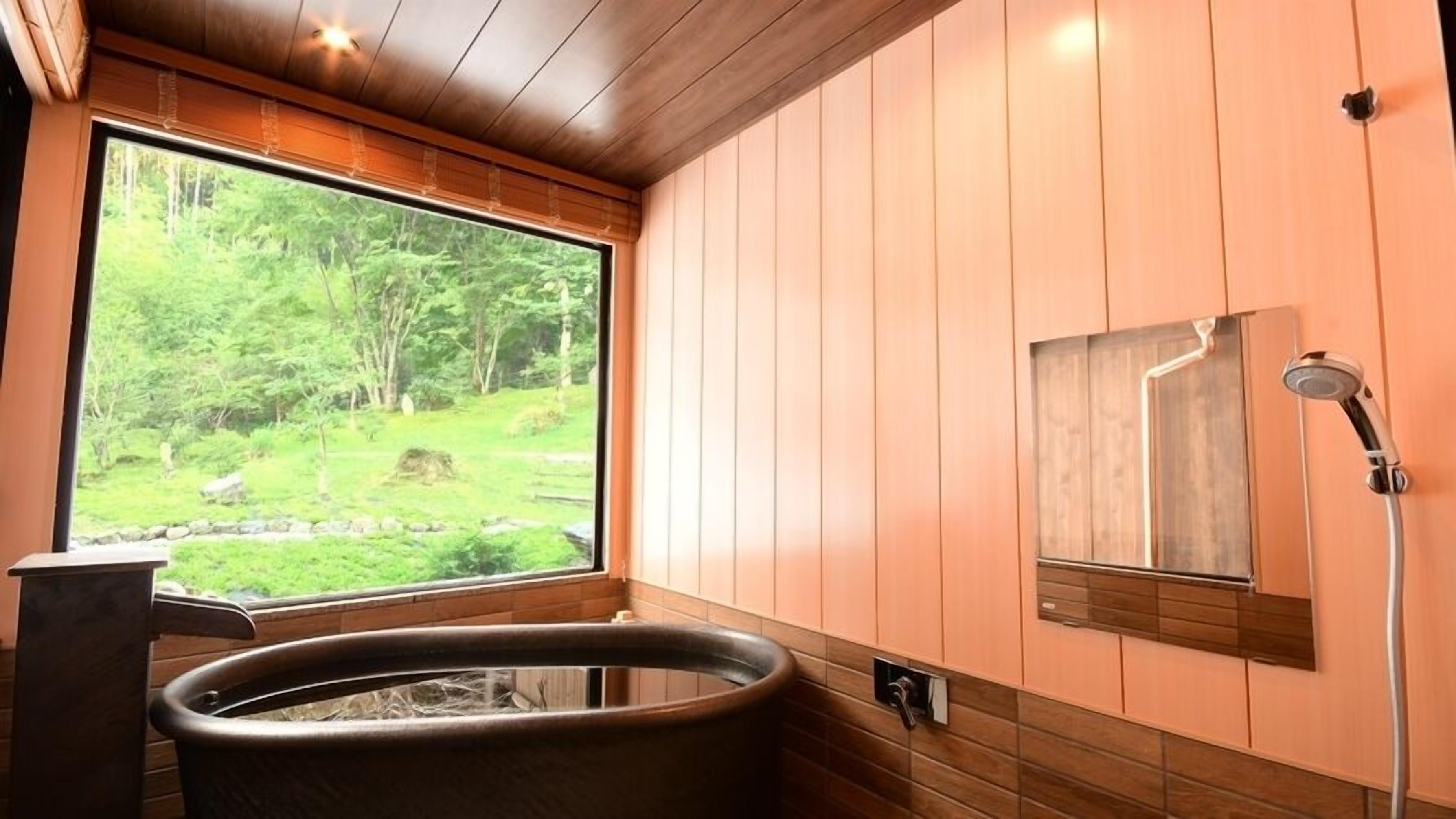 Un baño con paneles de madera, una bañera de hidromasaje, una ventana con vistas al bosque y una ducha.