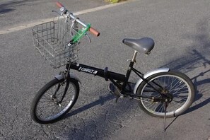 A stationary bicycle with a front basket and a rear rack, parked on a paved surface. - Idaimae Green Hotel (Saga)