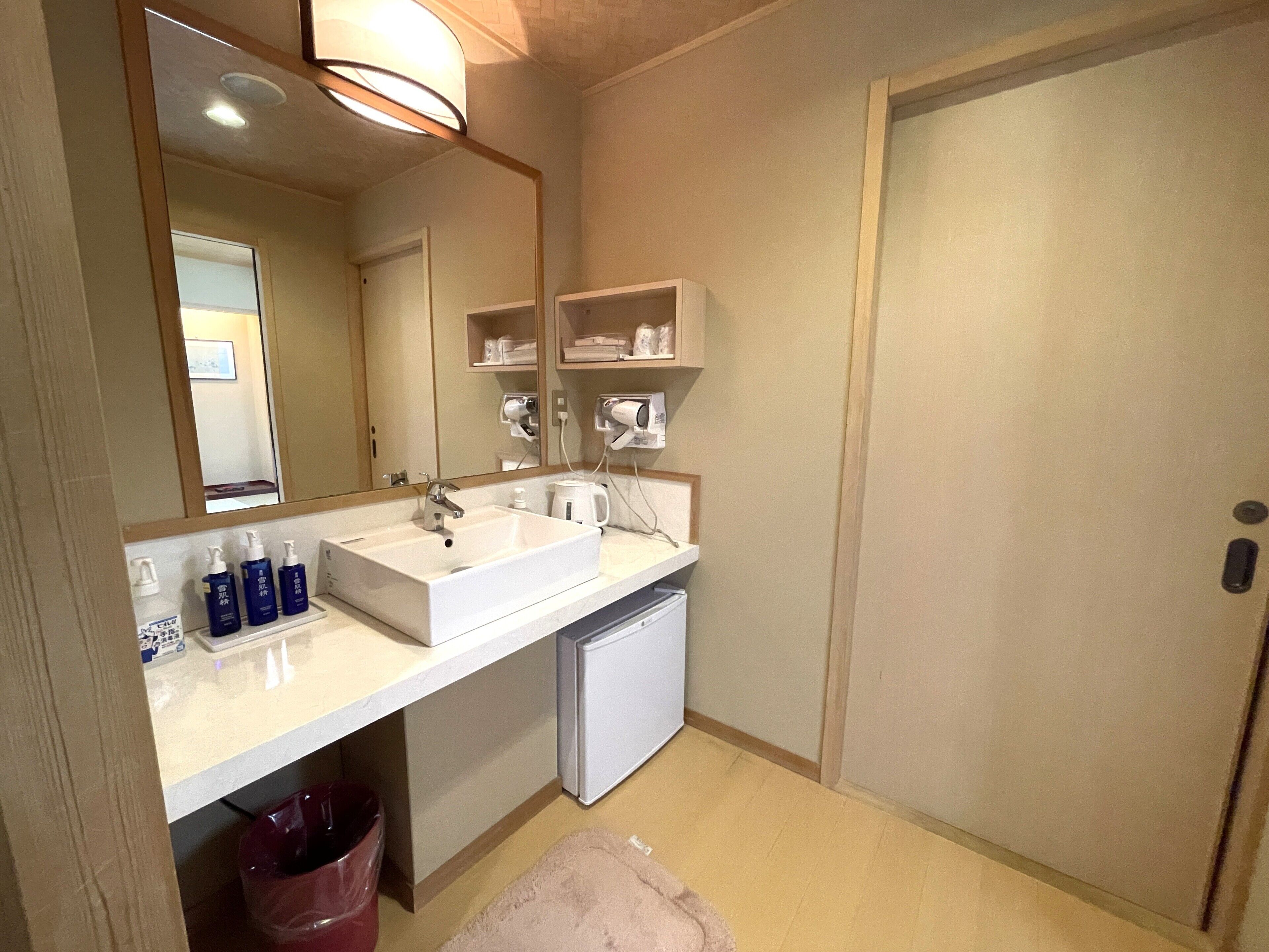 Un baño con lavamanos, espejo y perchero para toallas.
