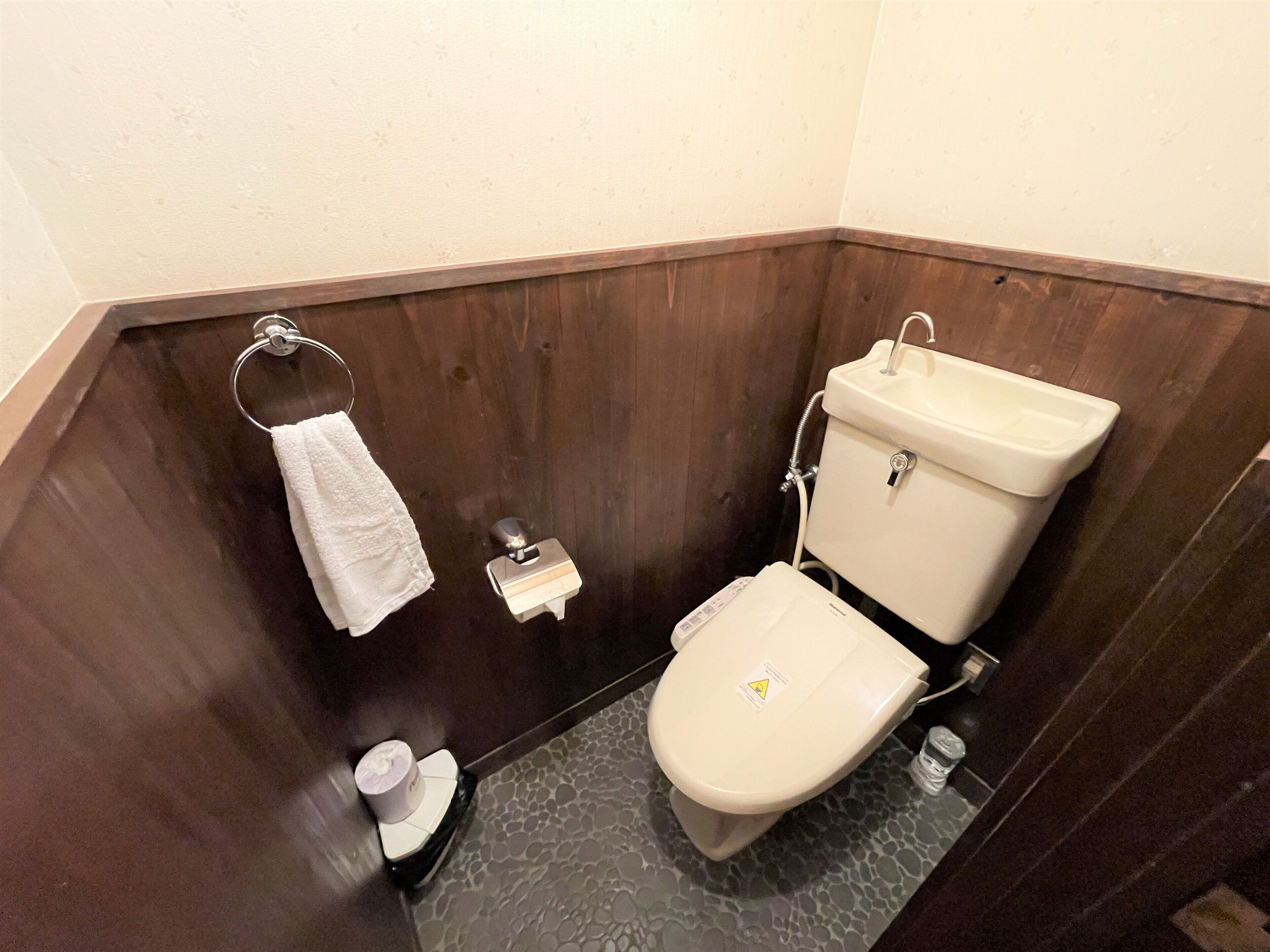 Un baño con inodoro, toallero y un pequeño cubo de basura.