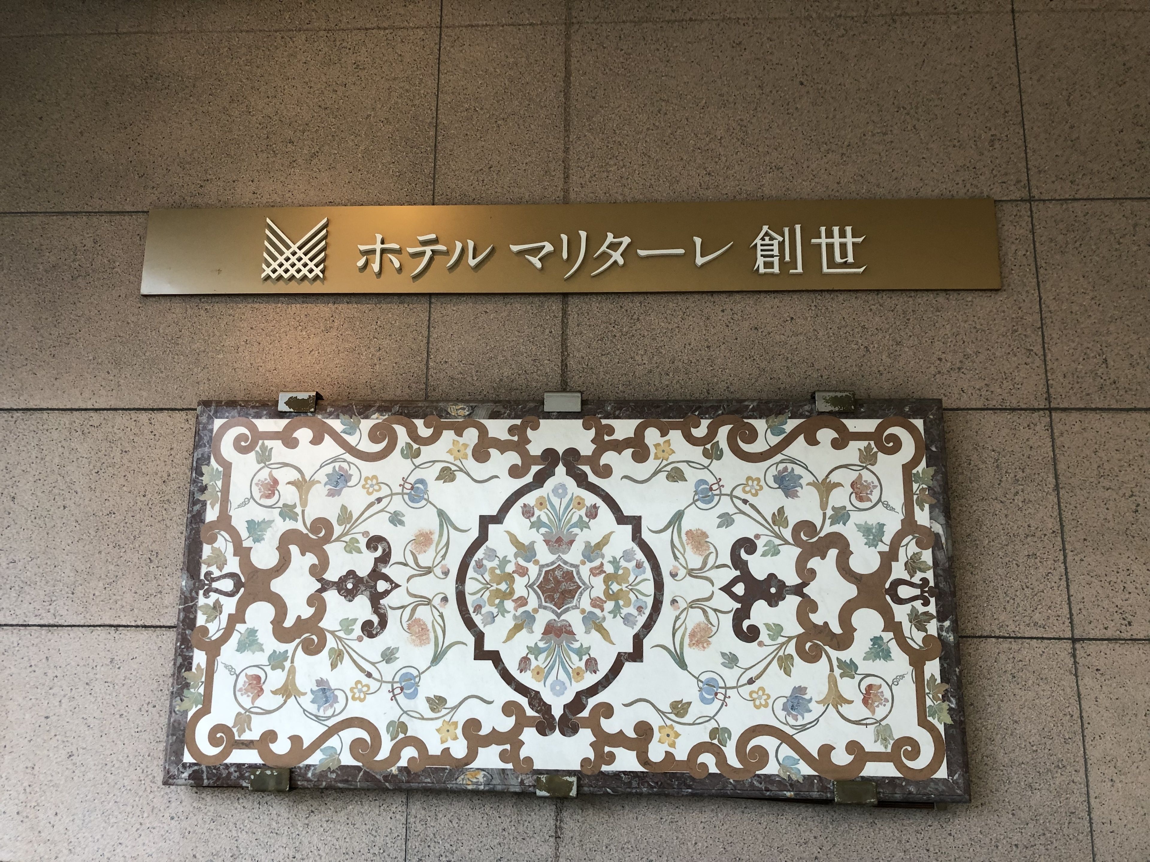 A sign with Japanese characters and a decorative tile below it.