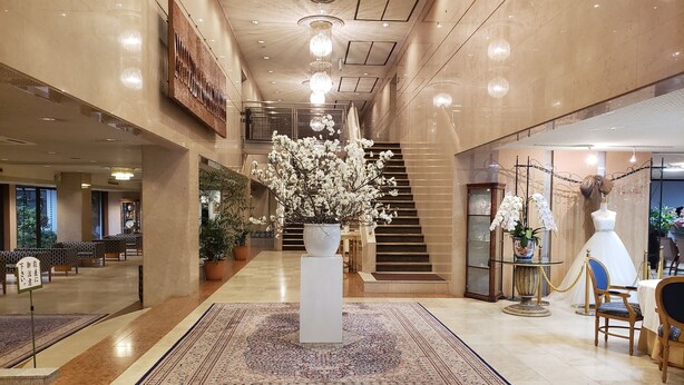 A spacious lobby with a central staircase, potted plants, and a mannequin in a dress. - Hotel Marital Sousei Kurume (Kurume)