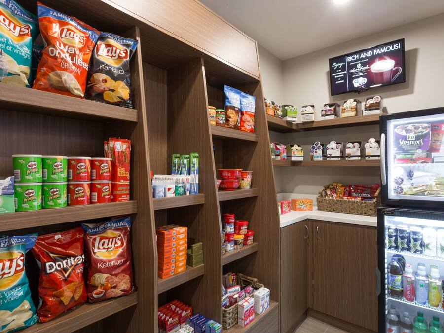 Ein Verkaufsbereich für Snacks und Getränke in einem Geschäft, mit Regalen voller Lay's, Pringles, Doritos und anderer Snacks.
