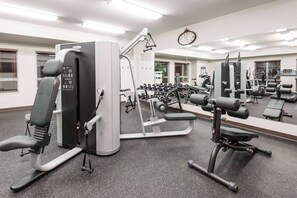A gym with various exercise equipment, including a leg press machine, dumbbells, and a bench press. - Microtel Inn & Suites By Wyndham Fort St John (Fort St. John)