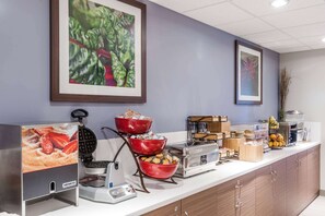 A buffet setup with various food items and a waffle maker. - Microtel Inn & Suites By Wyndham Fort St John (Fort St. John)