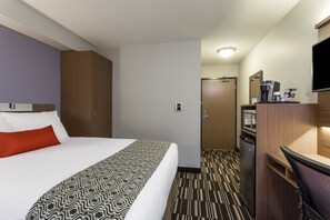 Een hotelkamer met een bed, een bureau, een koffiezetapparaat en een televisie.