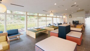 A modern hotel lobby with seating areas, a television, and a view of the outdoors.