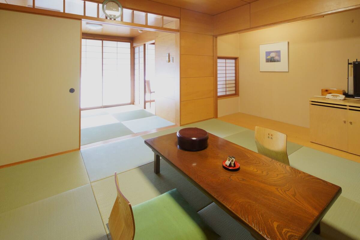 A traditional Japanese room with tatami flooring, a wooden table, and a television.