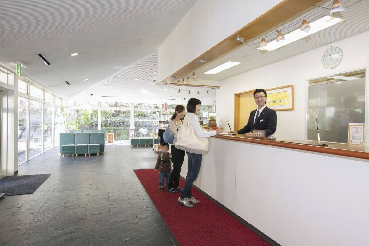 A reception area with a receptionist, a family, and a child.