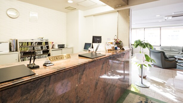 A reception area with a marble counter, a computer, a printer, and a bookshelf. - Hashimoto Park Hotel (Sagamihara)