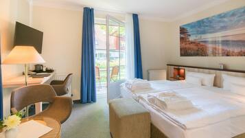 Habitación de hotel con cama, escritorio, silla, lámpara, un cuadro y vistas al exterior.