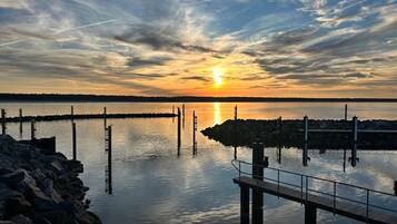 A pier extending into calm water with a sunset in the background.