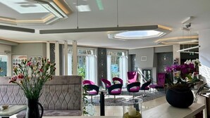 Un intérieur moderne comprenant un espace salon, un comptoir d’accueil et une grande fenêtre.